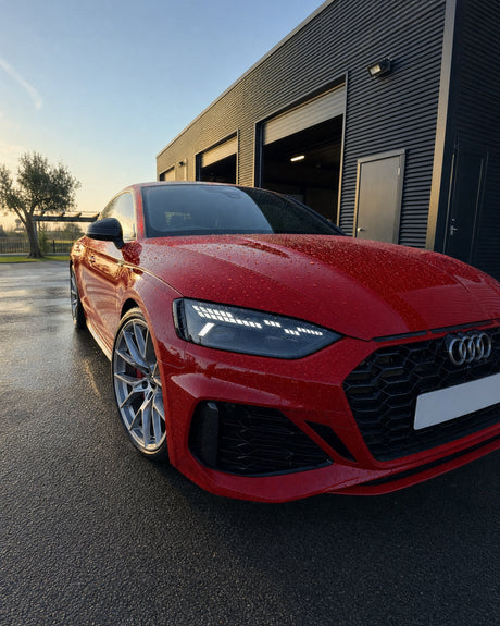 Frisch gewachster roter Audi RS 5, das Wasser perlt in runden Tropfen auf der tiefroten, spiegelnden Motorhaube ab.