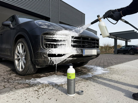 Schaumkanone sprüht Koch-Chemie Vorreiniger B auf dunklen Porsche Cayenne vor dem Warehouse — Vorwäsche-Start