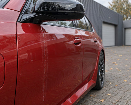 Detailing1 auto drogen — naloopwater uit de spiegel droogt op tot kalkvlekken op het portier van een rode BMW M5