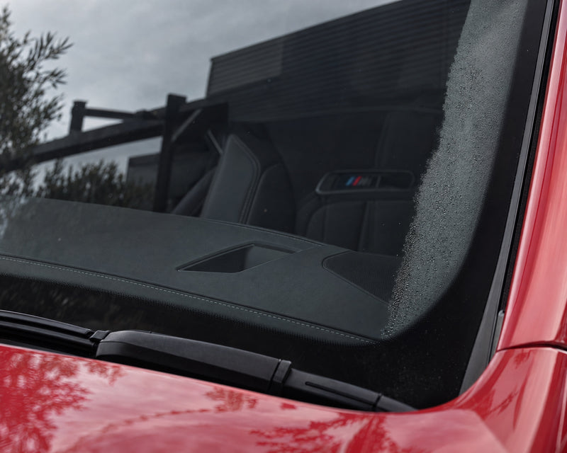 Heldere binnenruit van een rode BMW M5 na het reinigen, bij de A-stijl nog wat condens — te zien in het artikel „Auto beslaat van binnen: waarom een schone ruit langer helder blijft”